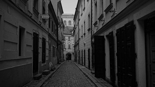 Narrow paved alley with tall, narrow older buildings, monochrome, old town of Bratislava