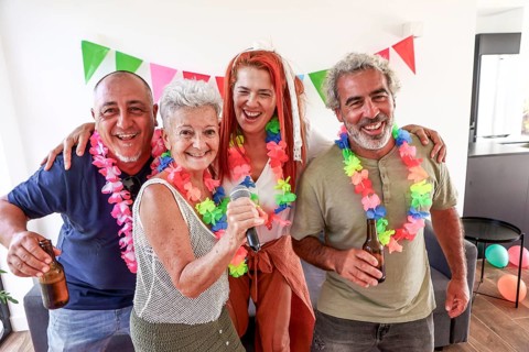 Elderly group of friends, dressed in colorful leis, celebrate at a vibrant over-50's party, singing