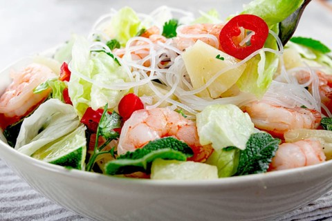 Thai salad with shrimp and rice noodles, pineapple slices, coriander and mint leaves, on a white