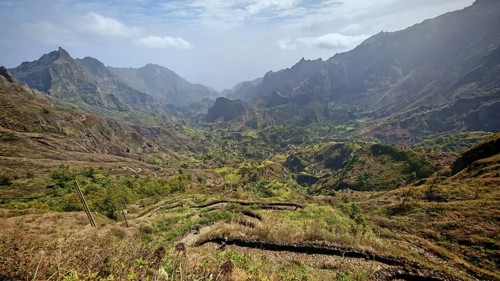 Panoramic, spectacular view over a valley with a winding path, hiking trail and mountains in the