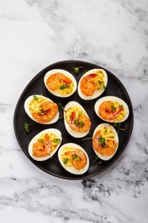 Boiled eggs stuffed with yolk and seasoned with mayonnaise, stuffed eggs with shrimp, on a black