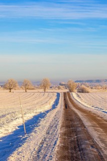 Slippery country road with snow and ice in a rural landscape by fields a cold winter day Sweden