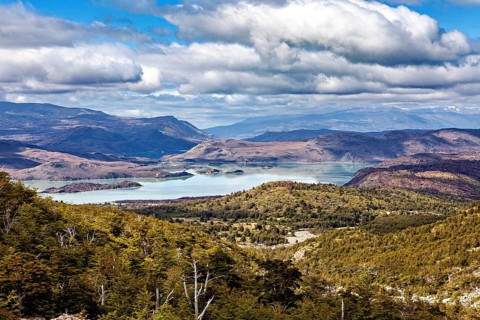 Sweeping panoramic view of a lake surrounded by mountains under a cloudy sky, The landscape of