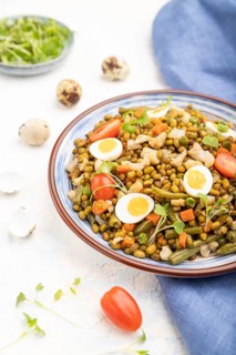 Mung bean porridge with quail eggs, tomatoes and microgreen sprouts on a white concrete background