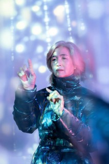 An elderly Asian woman engaging with a digital interface in the metaverse, highlighting the