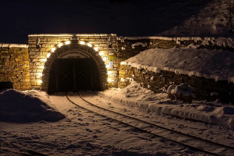 Illuminated mouth hole from Markus-Röhling-Stolln visitor mine in the snow, historical origin to