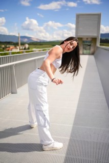 Vertical photo of a caucasian young woman dancing urban choreography on a bridge