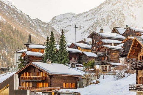 Snow-covered old farmhouses, large wooden cross, historic town center, Grimentz, Val d'Anniviers,