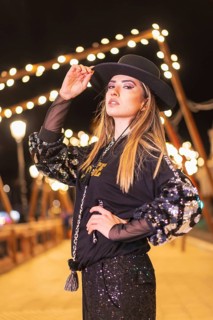Christmas lights in the city, Caucasian blonde girl dressed in black and with sequins posing for