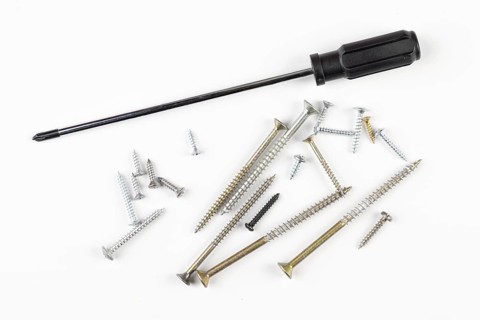 Screwdriver and screws on light background, tool collection