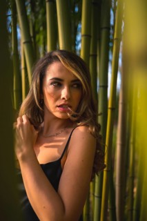 Portrait of a Caucasian girl in a black dress in a bamboo forest