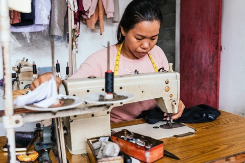 A asian seamstress focuses on sewing clothes in a workshop using a vintage sewing machine. Tools