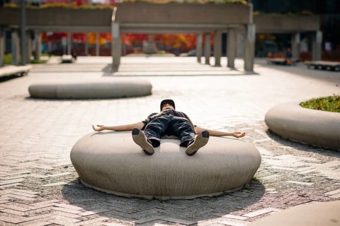 Unrecognizable man lying on a concrete structure, embracing the serene urban landscape in Montreal