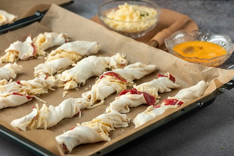 Dough rolls with ham and cheese on a baking tray to prepare for baking