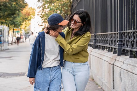 A joyful lesbian couple shares a loving moment while walking along a city street. They embrace,