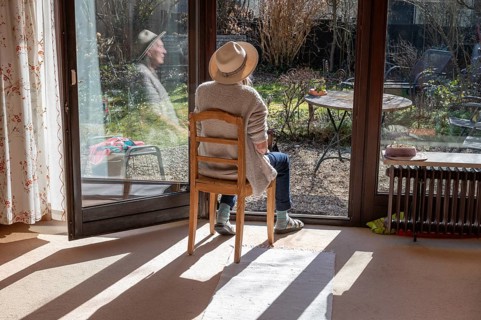 Woman wearing hat sunbathing with patio door open, Bavaria, Germany