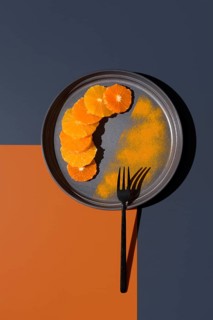 Sliced oranges and tangerines arranged creatively on a gray plate with contrasting orange and dark