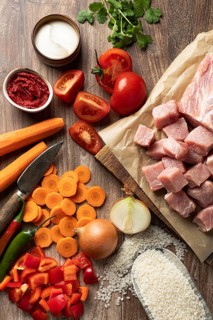 Top view of fresh ingredients arranged for preparing Hungarian pork goulash with rice. The image