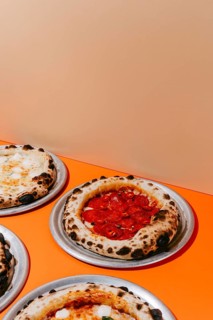 Wood-fired pepperoni pizza topped with salami, mozzarella, tomato sauce, and chili pepper. Served
