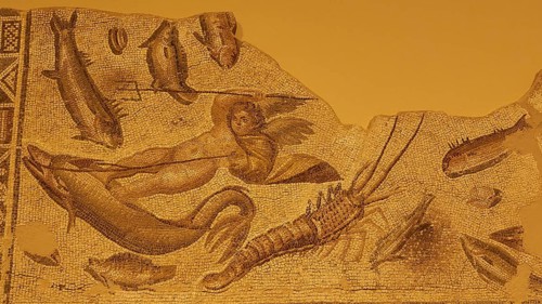Ancient mosaic with mythological figure and various fish and marine animals in pale shades of