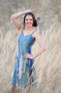 A young woman in a colorful dress poses in a field of reeds with one hand on her hip, Bavaria