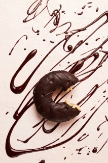 Donuts, in chocolate glaze, on a beige background, with liquid chocolate