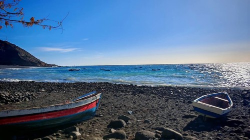 Small rocky beach with fishing boats, bright blue sky and sea, hiking, Tarrafal de Monte Trigo,