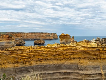 Stunning coastal rock formations under a cloudy sky in the Twelve Apostles, Australia. Layers of