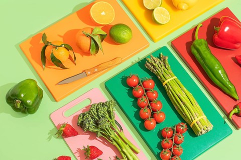 A vibrant display of fresh fruits and vegetables on colorful cutting boards. Includes oranges,