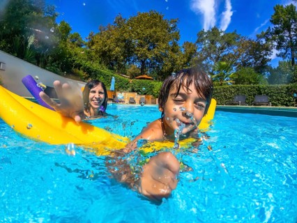 Mother and child enjoying active summer vacation, a boy splashing water from his mouth, swimming