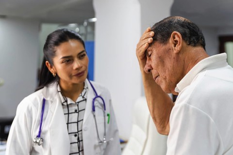 An elderly male patient is attentively receiving professional medical care from a young female