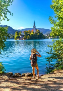 Female tourist wearing backpack and straw hat admiring the pilgrimage church of the assumption of