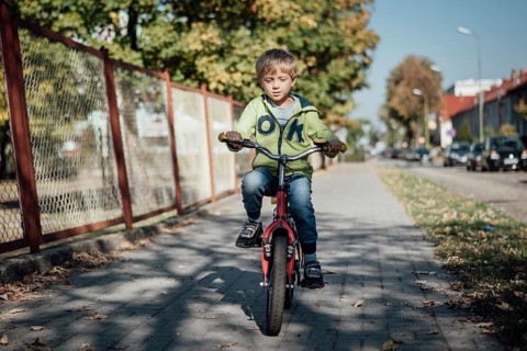 Little boy on a bicycle ride on a pavement in a town