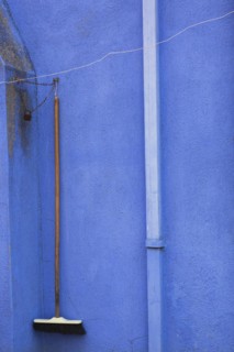 Downspout and broom locked with chain on blue stucco exterior house wall, Burano Island, Venetian