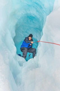 Mountaineer moving up ice cave, Fox Glacier, Westland National Park, South Island, New Zealand