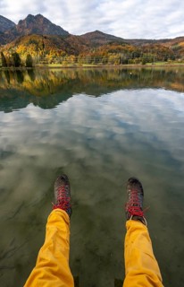 Feet with hiking boots, autumn landscape, reflection in Lake Kochel, Upper Bavaria, Bavaria,