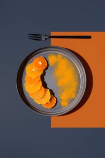 Sliced oranges and tangerines arranged on a gray plate with a contrasting orange and dark blue