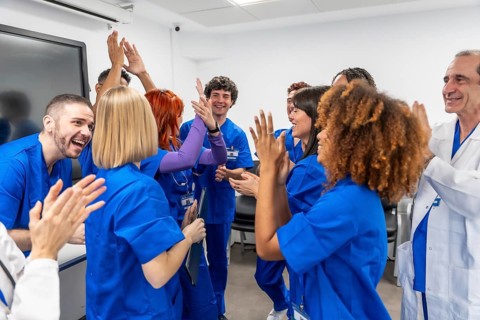 Diverse healthcare team of doctors, nurses and medical students celebrating, clapping and high