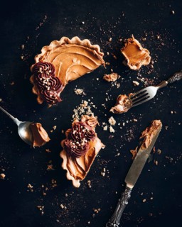 Overhead view of a tempting speculoos tart, partially eaten, with crumbs scattered on a dark
