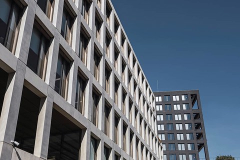 A perspective view of modern urban office buildings with geometric designs against a clear blue sky