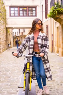 Pretty latin woman with sunglasses doing bicycle sightseeing in the city through the old town.