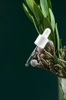 A close-up image of a pipette bottle filled with transparent micellar water, placed alongside fresh