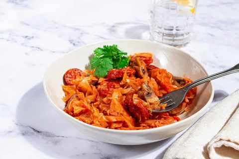 Bigos, Polish dish bigos, on a marble table, stewed meat with cabbage, chorizo sausages, mushrooms,