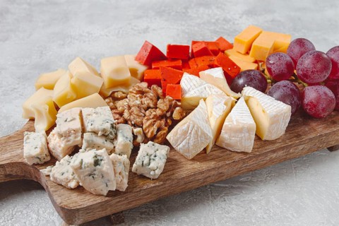Assorted cheese on a wooden board, with grapes and walnuts, appetizer, no people