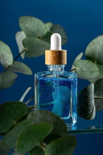 A cooling blue face care serum or oil targeted for men, displayed in an elegant dropper bottle