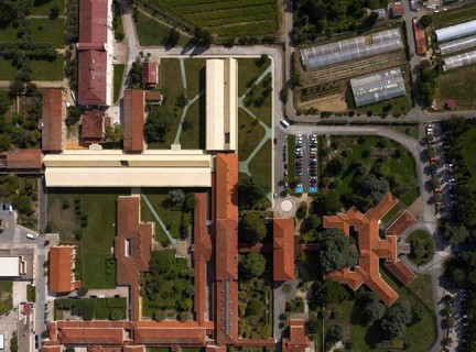 Aerial view of a large hospital with interconnected buildings surrounded by greenery, roads, and