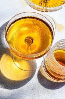 Elegant glassware displays Georgian amber wine rich hue on a textured surface. The deep golden