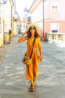 Tourist wearing yellow jumpsuit and hat walking down street in kranj, slovenia, enjoying summer