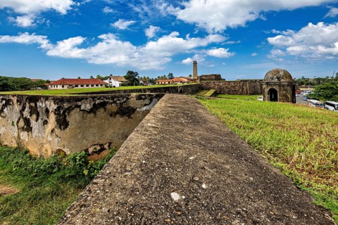 Fortress wall with a view of buildings in the background under a cloudy sky, The fortress of Galle