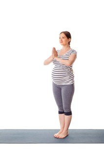 Pregnancy yoga exercise, pregnant woman doing yoga asana Tadasana Mountain pose with namaste